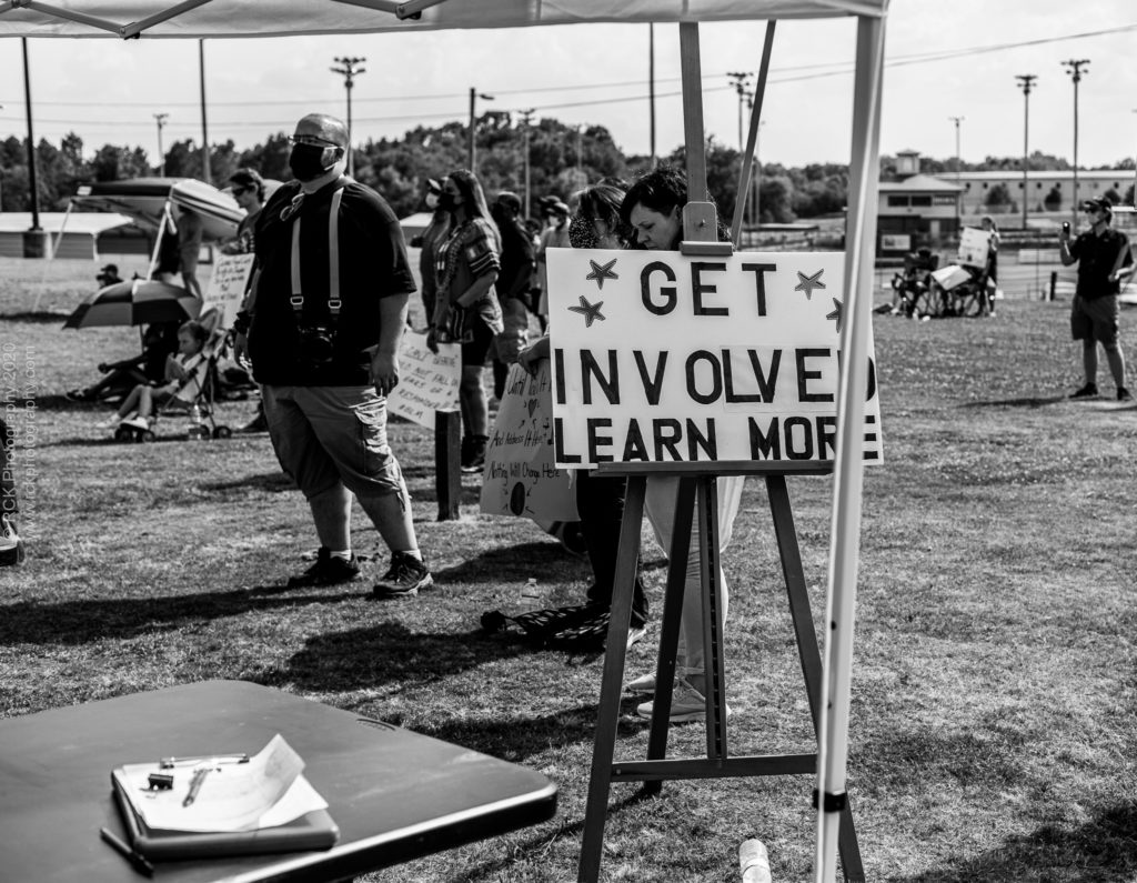  image of a stand holding a sign that reads "Get Involved Learn More" with