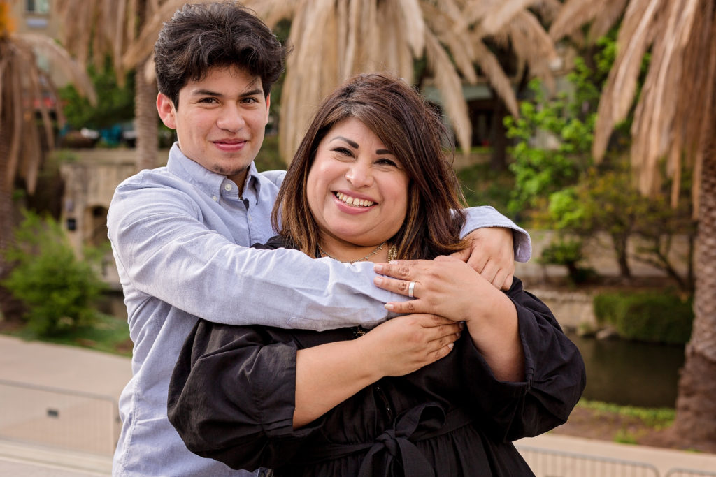 Young Hispanic man hugging his mother from behind captured by a portrait photographer