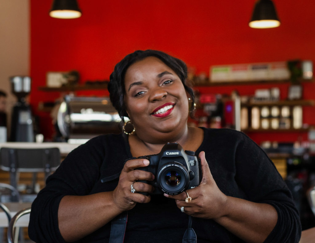 African American female portrait photographer holding a Canon Camera