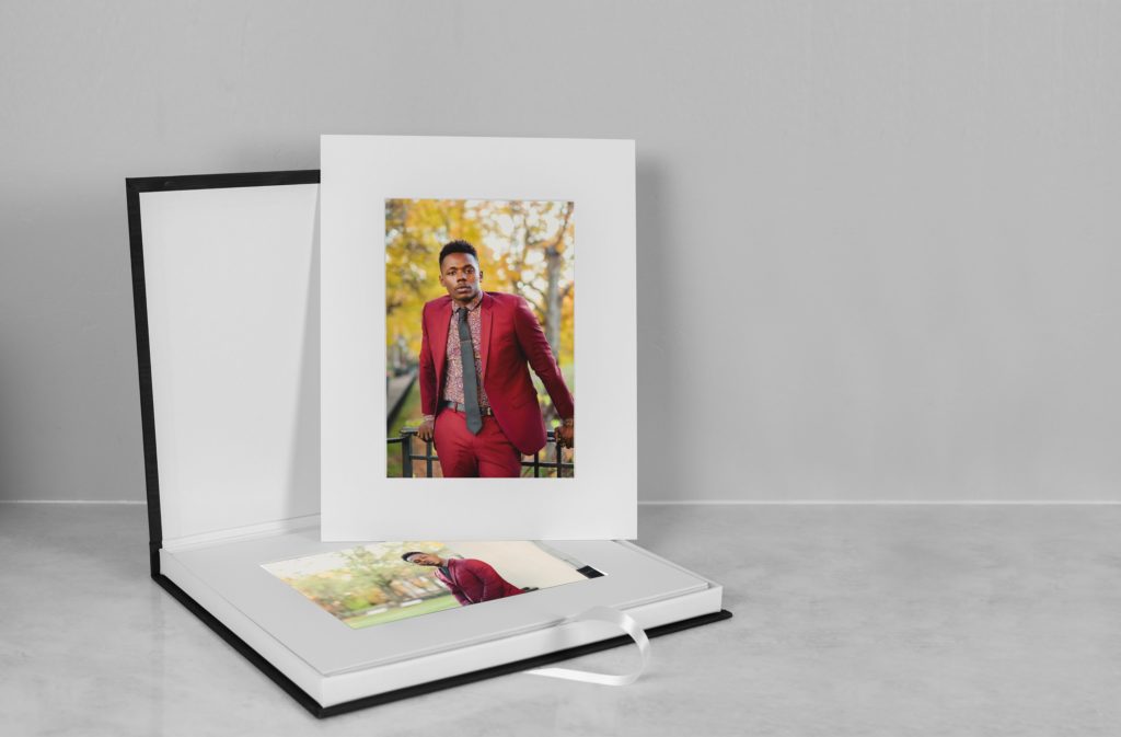 a matted photo on top of a slip in matted album showcasing printing photos in an album of a Black Man wearing a red suit